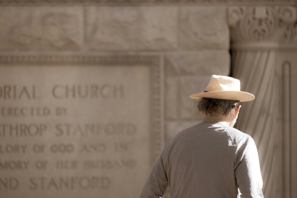 a man wearing a hat walking in front of a memorial. VISIONS: GETTING IN TOUCH WITH YOUR "DAY DREAMS"
